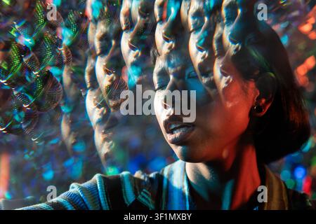 Jeune chanteuse latine interprétant près d'un microphone, capturée avec un effet de lentille kaléidoscopique, des lumières de bokeh rêveuses et des réflexions prismatiques i Banque D'Images