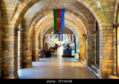 Arcade en pierre calcaire voûtée avec des drapeaux de l'Azerbaïdjan dans la zone piétonne de la rue Nizami, Bakou, Azerbaïdjan. Banque D'Images