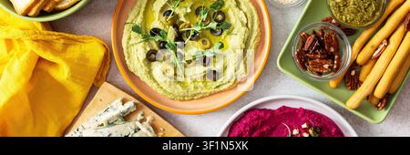 Une planche de charcuterie vibrante présente du brocoli, du curcuma, du houmous classique et de la betterave, associés à des olives, craquelins, et garnitures fraîches, parfait pour Banque D'Images