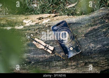 Smartphone affichant une application de méditation sur une bûche en bois usée à côté d'un bâtonnet d'encens brûlant. Fonction de bien-être numérique, gestion du temps d'écran Banque D'Images