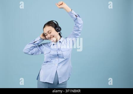 Jeune femme joyeuse portant des écouteurs et dansant sur sa musique préférée dans la st... Banque D'Images