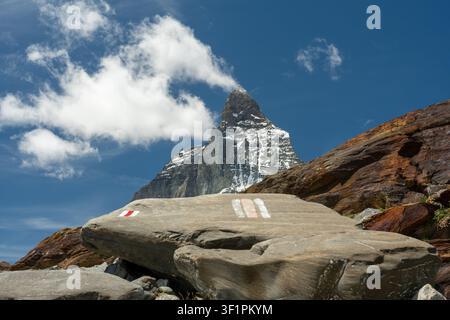 Le sommet du Matterhorn s'élevant derrière un rocher marqueur de sentier par une journée ensoleillée Banque D'Images