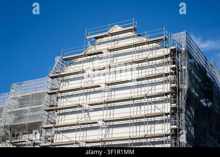 Plateformes d'échafaudage modulaires en acier surélevées érigées sur la façade extérieure d'une maison en rénovation représentant des solutions de l'industrie de la construction Banque D'Images