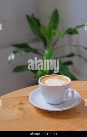 Une tasse de cappuccino fraîchement servi sur une table en bois dans un café cosy. Banque D'Images