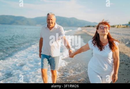Couple mûr habillé de manière décontractée profitant d'une promenade ensemble au bord de la mer Banque D'Images
