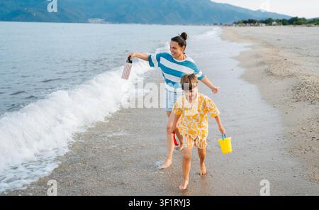 Mère et fils courant ensemble sur Sunset Beach Banque D'Images
