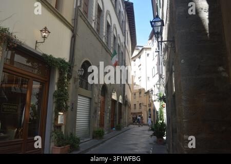 Ruelle charmante avec des bâtiments en pierre, des lanternes et des plantes vertes dans le centre historique d'une ville italienne. Banque D'Images