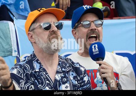 Jason Sudeikis, à droite, et son co-star de "Ted Lasso" Brendan Hunt parlent dans un microphone marqué de la Coupe du Monde de la FIFA 2026 tout en encourageant la foule au GEHA Field du stade Arrowhead à Kansas City, Missouri, le 11 juillet 2026. Sudeikis et Hunt sont apparus avant le match de quart de finale de la Coupe du Monde de la FIFA 2026 entre l'Argentine et la Suisse, les deux hommes portant des casquettes des Kansas City Royals en hommage à la ville hôte. (Photo de Travis Heying/The Wichita Eagle/TNS/Sipa USA) Banque D'Images