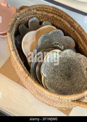 Panier tissé avec plusieurs assiettes en céramique façonnées en forme de fleurs exposées à l'intérieur. Photo mobile Banque D'Images