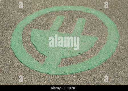 Symbole de station de recharge pour véhicule électrique vert peint sur la surface de la route en asphalte. Banque D'Images