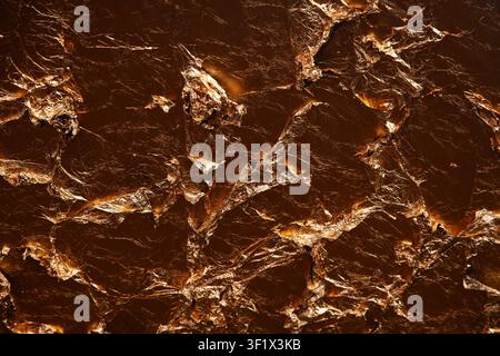 Fond texturé bronze sombre abstrait composé de papier d'aluminium métallique froissé et de morceaux de cuivre vieillis avec des ombres profondes et des reflets Banque D'Images