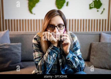 femme caucasienne anxieuse, inquiète, triste, sérieuse, frustrée, contrariée. dame fille à l'intérieur à la maison femme en train de parler au téléphone portable conversation écoute b Banque D'Images