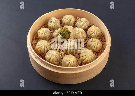 Dumplings de porc cuit à la vapeur et légumes de bourrache dans un cuiseur à vapeur en bambou, petits pains baozi chinois à peau fine et cristalline Banque D'Images