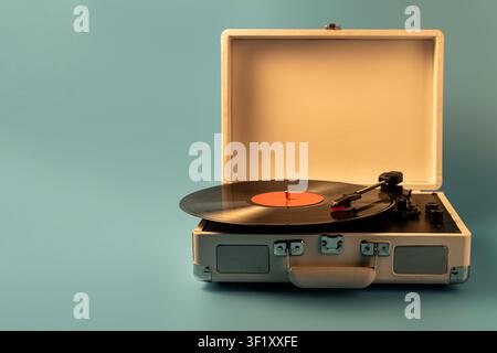 Un tourne-disque classique de style valise est ouvert, présentant un vinyle noir avec une étiquette orange et le bras de lecture prêt à jouer Banque D'Images
