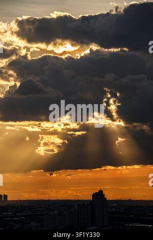 Le soleil brille intensément alors qu'il se couche à travers les nuages superposés. Banque D'Images