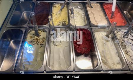 Présentation de magasin de gelato offrant un assortiment de saveurs de glace colorées dans des contenants en métal brillants, invitant les clients à choisir une gourmandise rafraîchissante Banque D'Images