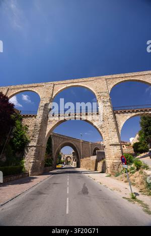 Les arches d'un aqueduc historique créant un passage architectural au-dessus d'une route à Teruel, en Espagne Banque D'Images