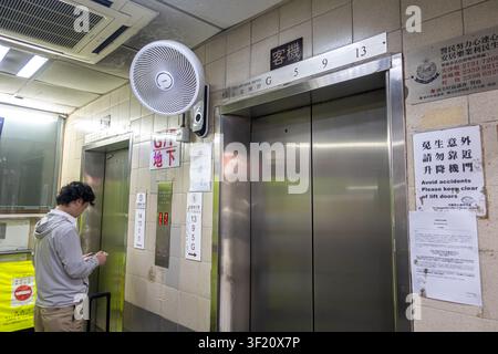 Une personne attendant un ascenseur passager dans un bâtiment commercial de la villa Mirador à Hong Kong. Panneau visible avec indicateurs d'étage des ascenseurs Banque D'Images