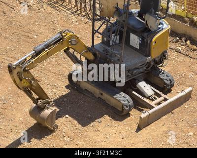 Vue d'une mini-excavatrice jaune garée sur un chantier de construction en terre à Istanbul, Istanbul, Turkiye. Banque D'Images