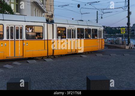 Tramway jaune passant le long des quais du Danube à Budapest Banque D'Images