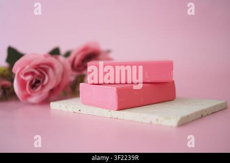 Deux savons roses sur une surface de couleur claire avec des roses Banque D'Images