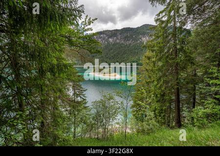 Une vue panoramique grand angle du magnifique lac turquoise de l'Eibsee en Bavière, Allemagne, encadré par des pins verts luxuriants. Au milieu du lac alpin Banque D'Images