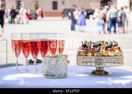 Installation élégante de catering en plein air sur une nappe blanche, avec des boissons pré-remplies et des hors-d'œuvre prêts pour une célébration Banque D'Images