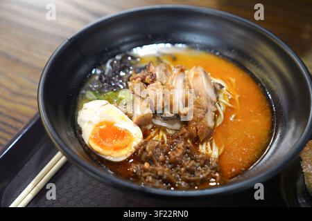 Close-up de ramen épicé au poulet, œuf mollet, nouilles et bouillon riche servi dans un restaurant de street food. Concept de cuisine asiatique populaire. Banque D'Images