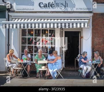 Des personnes assises à des tables devant le Café Fresh sur Market Place, dans le centre-ville de Romsey, dans le Hampshire, en Angleterre, Royaume-Uni. Banque D'Images