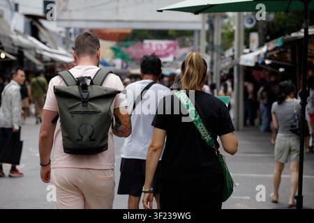 BANGKOK, THAÏLANDE - 12 JUILLET 2026 : des backpackers explorent le marché de Chatuchak à Bangkok, vue de dos. Banque D'Images