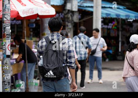 BANGKOK, THAÏLANDE - 12 JUILLET 2026 : Randonneur masculin explorant un marché en plein air à Bangkok, vue de dos Banque D'Images