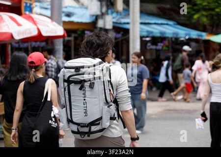 BANGKOK, THAÏLANDE - 12 JUILLET 2026 : Randonneur masculin explorant un marché en plein air à Bangkok, vue de dos Banque D'Images