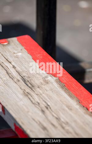 Détail de la surface d'un banc rustique avec un bord peint en rouge et une mise au point peu profonde Banque D'Images