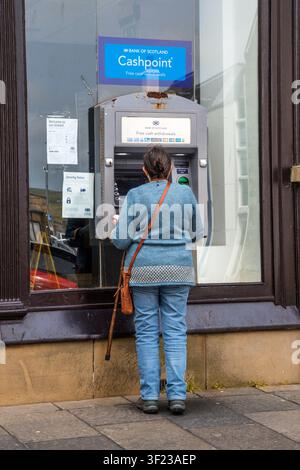Femme retirant de l'argent d'un distributeur Bank of Scotland à Lerwick, Shetland. Banque D'Images
