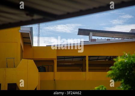Un bâtiment moderne et vibrant avec une façade jaune vif met en valeur l'architecture contemporaine et le développement urbain sous un ciel bleu parsemé de nuages Banque D'Images