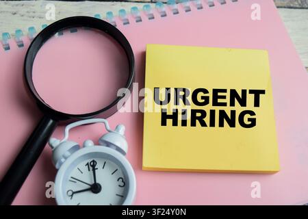 Concept de recrutement urgent écrit sur des post-it isolés sur une table en bois. Banque D'Images