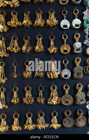 Une collection de diverses clés et porte-clés est disposée soigneusement sur un mur dans une boutique. Chaque pièce présente un design unique. Le cadre semble être un marché Banque D'Images