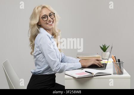 Jeune femme souriante travaillant sur un ordinateur portable dans un bureau moderne, concept d'affaires Banque D'Images
