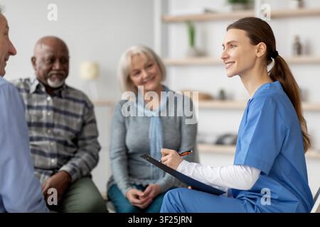 Jeune infirmière souriante aidant des patients âgés dans une clinique de santé, concept de soins de santé Banque D'Images