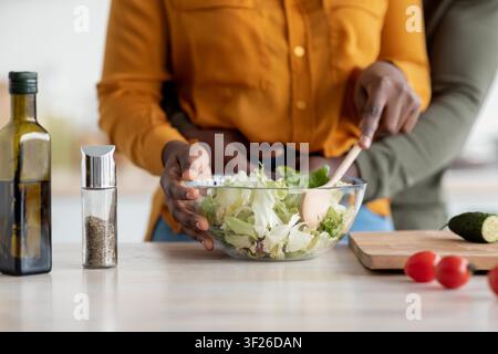 Couple préparant une salade ensemble dans une cuisine moderne, concept de cuisine partagée Banque D'Images