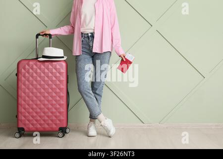 Jeune femme avec une valise rose, un passeport et une carte d'embarquement, prête pour les voyages et les vacances Banque D'Images