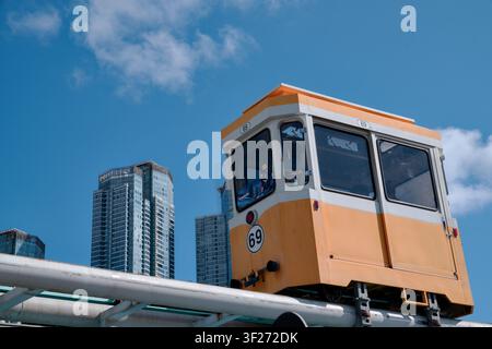 BUSAN, CORÉE DU SUD - 10 OCTOBRE 2025 : Une petite capsule aérienne jaune passe devant des gratte-ciel de luxe et des immeubles modernes à Haeundae Banque D'Images