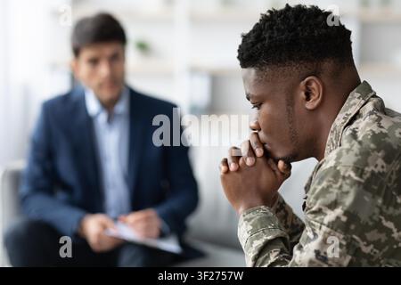 Soldat noir inquiet discutant de la santé mentale avec un thérapeute au bureau, concept de soins de santé Banque D'Images