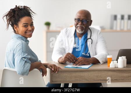 Patiente noire souriante en consultation avec un médecin dans une clinique de santé Banque D'Images