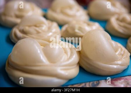 Un gros plan de boules circulaires non cuites de pâte à pain plat roti canai huileuse reposant sur un tapis bleu, prêtes à être frites. Banque D'Images
