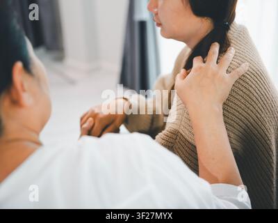 Close-up d'une mère asiatique réconfortant sa fille adulte avec une main sur l'épaule et tenant les mains à la maison, concept d'empathie, de soutien émotionnel, de conseil, Banque D'Images