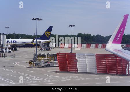 Avions Ryanair et Wizz Air garés au terminal avec l'équipement de soutien au sol sur le tarmac ensoleillé de l'aéroport de Gatwick à Londres, Royaume-Uni. Banque D'Images