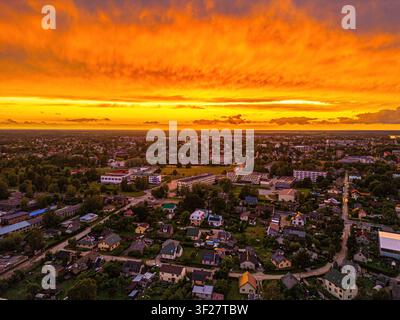 Vue aérienne de la ville de Jelgava avec des bâtiments résidentiels et une végétation luxuriante sous un ciel de coucher de soleil orange vif à Jelgava, en Lettonie. Banque D'Images
