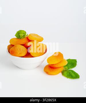 Pile d'abricots secs avec des feuilles vertes, isolés, tas d'abricots secs dans un bol, groupe de fruits d'orange sains, collation de dessert bio sucrée, nourriture de régime saine Banque D'Images