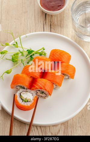 Roulés de sushi au saumon frais style Philadelphia sur une assiette blanche Banque D'Images